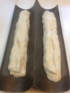 Bread dough rising in a perforated French bread pan